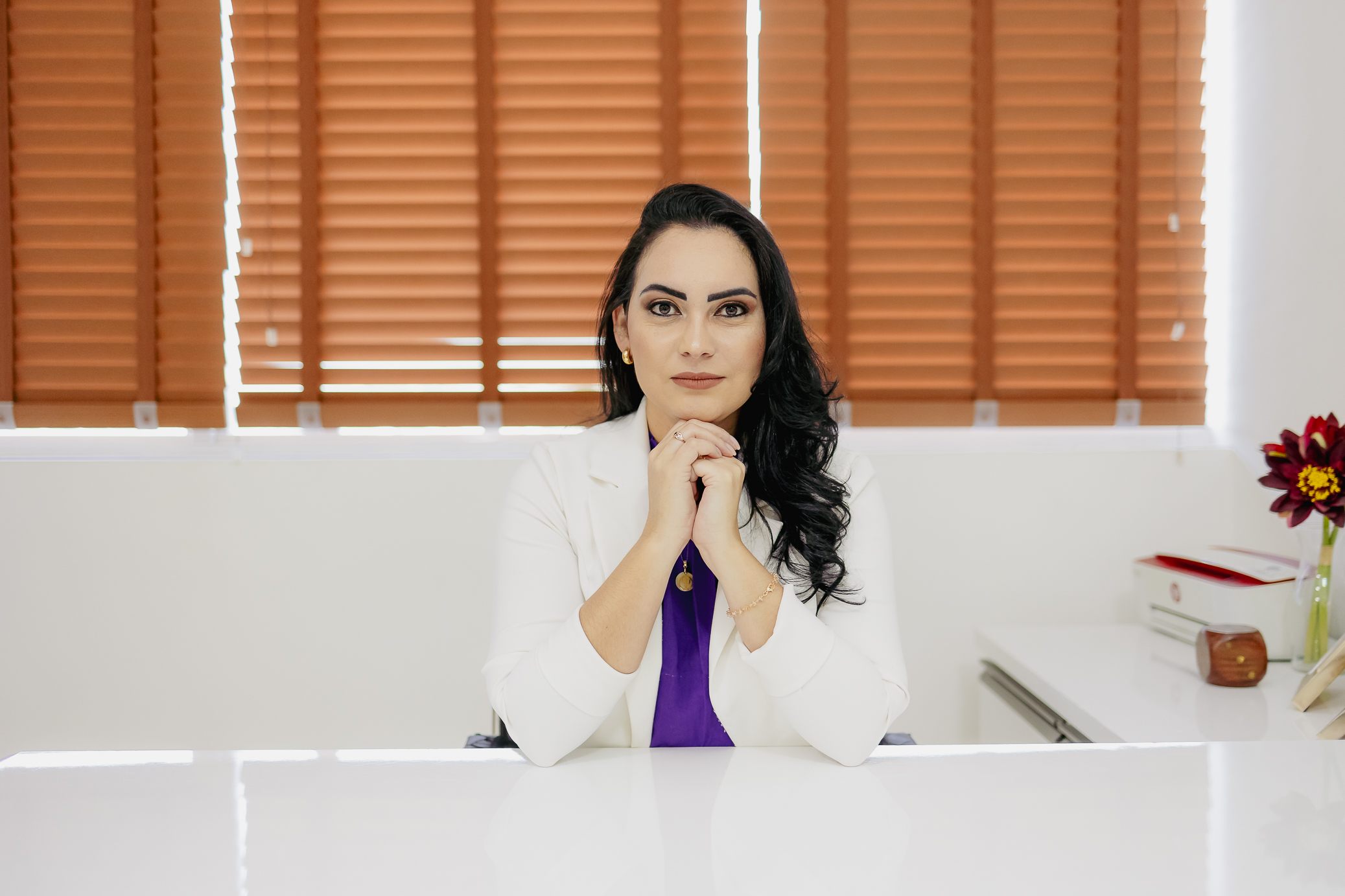 Retrato fotográfico da Psicóloga Leila Chaves com jaleco e olhar acolhedor em seu consultório